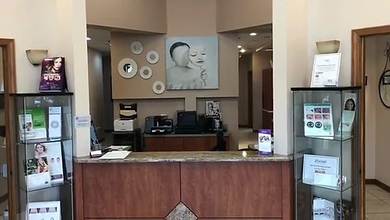 The reception area at B&R Dentists: a granite-topped front desk, display cabinets and framed artwork on warm neutral walls.